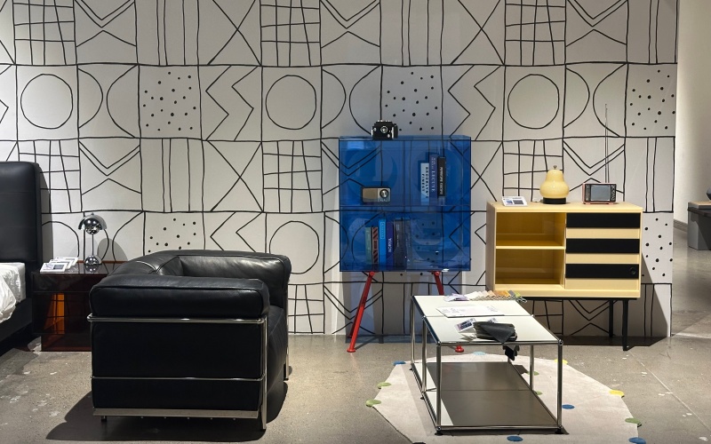 意梵盛栖家居展厅中的意式极简卧室场景，展示床、床头柜、灯具与艺术漆墙面的整体搭配效果